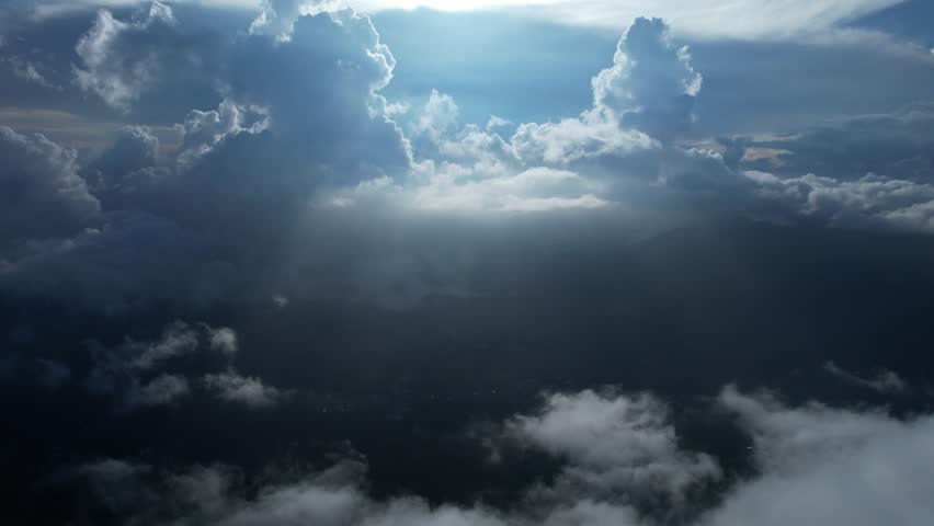 Stunning aerial shot with sunbeams piercing thick clouds, casting heavenly light over Indonesia