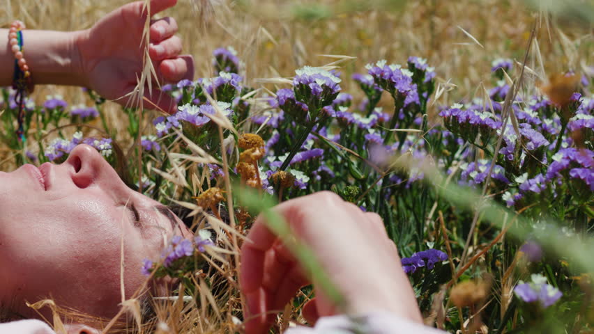 girl enjoying nature. relaxed woman in dress lying on blooming meadow, summer day, feeling nature.