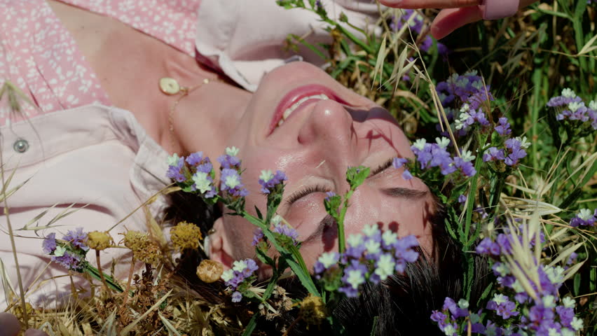 girl enjoying nature. relaxed woman in dress lying on blooming meadow, summer day, feeling nature.