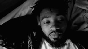 Contemplative young African American man lying in bed gazing while in deep mental reflection, close-up face of a thoughtful black 20s person in monochrome, black and white - Powered by Shutterstock - Get 15% off with code: PIKWIZARD15