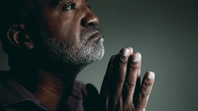 Earnest African American Elder Seeking Divine Guidance in Prayer, Eyes Shut and Hands Together, Senior Man in Deep Contemplation Asking for Help and Support - Powered by Shutterstock - Get 15% off with code: PIKWIZARD15