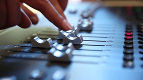 Close-up of sound technician adjusting levels on audio mixing console. Red light, sound check at the nightclub. Modern audio system. - Powered by Shutterstock - Get 15% off with code: PIKWIZARD15