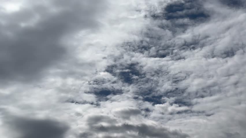 Bright cloudy sky with scattered fluffy clouds floating across a soft blue background. The image radiates a calm, airy atmosphere perfect for weather or nature themes. Dramatic clouds. 
