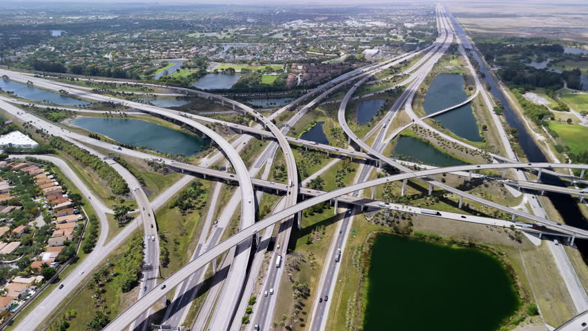 A raised highway interchange in Miami, bustling with the fast moving vehicles, showcasing U.S. transportation infrastructure under a cloudy sky. Close up view.