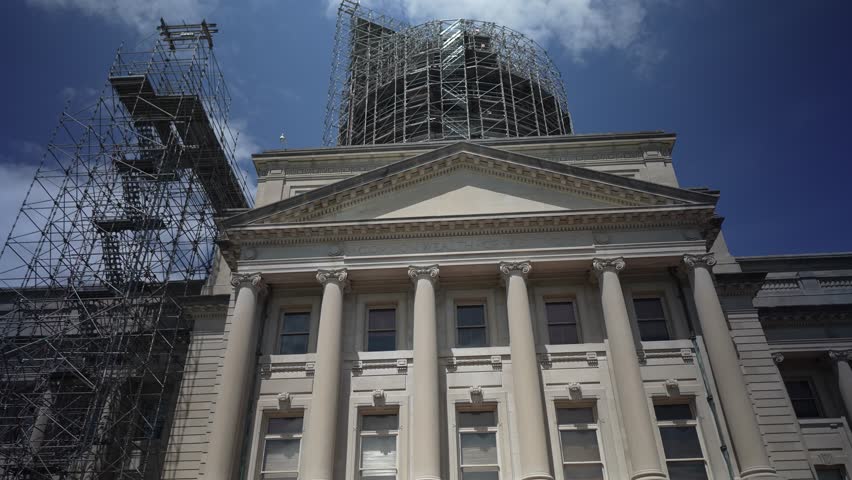 Scaffolding surrounds the Kentucky State Capitol in Frankfort as renovations are underway. The impressive architecture is visible against a blue sky.