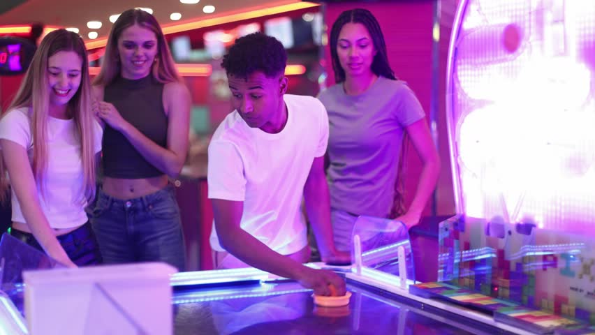 Friends sharing excitement while competing in air hockey match, moving quickly across colorful arcade game table with enthusiastic interaction and joyful energy