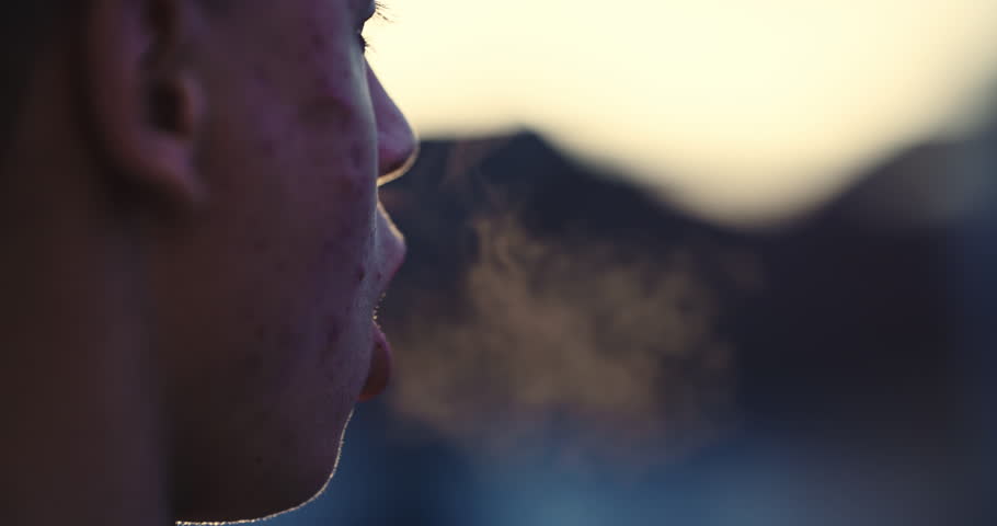 Young man with acne breathing hard after morning exercise backlit by sunrise sun, slow motion cinematic shot