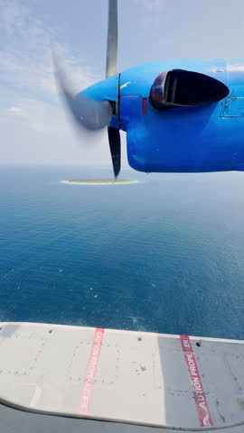 view from the water airplane window to the rotating propellers of the engine of a local airlines plane flying over the islands of Maldives, blue sky