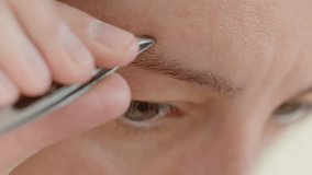 Close-up of woman plucking eyebrows with a metal tweezer. Home beauty routine - Powered by Shutterstock - Get 15% off with code: PIKWIZARD15