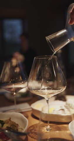Champagne tasting, The sommelier pours sparkling wine from the decanter into a beautiful glass, Wine glasses are on the table, stylish table setting, sparkling wine bubbles