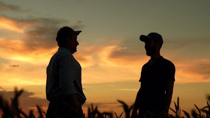 Business people partners shaking hands in field. Teamwork of business people in agriculture. Farmers men raise their hands clap their palms making deal, agricultural field. Teamwork of business people