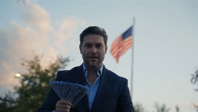 Portrait business man holding cash dollar bills front flag America. Big luck. Dollar cash money concept. Man hold cash money near flag usa. Financial luck and success. Businessman Holding Money - Powered by Shutterstock - Get 15% off with code: PIKWIZARD15