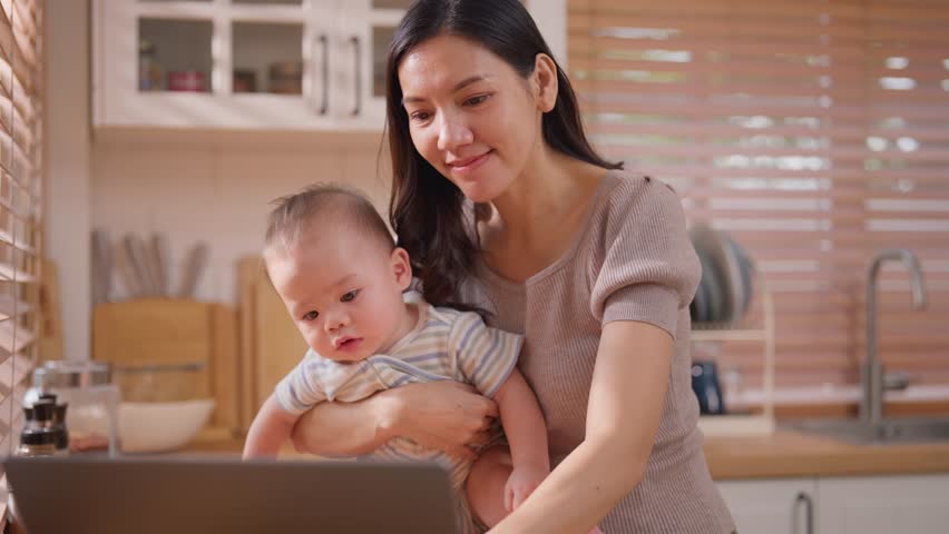 Asian single mother lovingly cares for and raises her baby boy in house. Attractive mom share tender moment holding newborn baby while working from home, creating warm and nurturing family environment