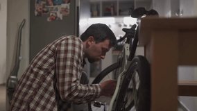 Cyclist mounting accessories on bike at home in studio apartment. Man sets up bike at home. Male repairs bicycle in living room gravel bike. Fixing your cycle yourself. DIY concept. Do it yourselves - Powered by Shutterstock - Get 15% off with code: PIKWIZARD15
