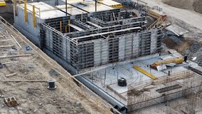 A detailed overview of the ongoing construction work for a new building foundation takes place in an urban setting. Workers manage various tasks involving heavy machinery and concrete  - Powered by Shutterstock - Get 15% off with code: PIKWIZARD15