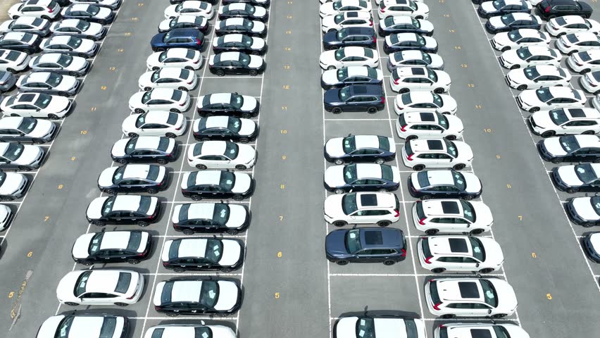 From above, the image displays the systematic organization of cars, emphasizing the inventory management within a car dealership, ready for sale or shipment.
