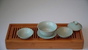 Cup or tea glass hot brew, he pours dried tea leaves into gaiwan on a wooden plate, placed on a wooden table, on a white background. Brewing Chinese tea in ceramic gaiwan during the tea ceremony.  - Powered by Shutterstock - Get 15% off with code: PIKWIZARD15