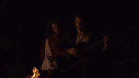 Couple enjoying a cozy campfire with guitar. - Powered by Shutterstock - Get 15% off with code: PIKWIZARD15