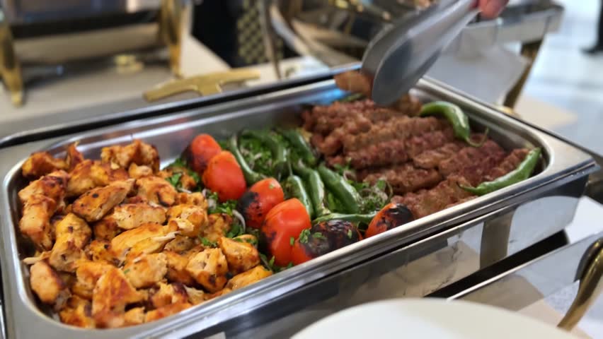 Delicious grilled kebabs and peppers being served on a white plate at a buffet in 4K. Great for food, hospitality, catering, or cooking visuals with vibrant detail.