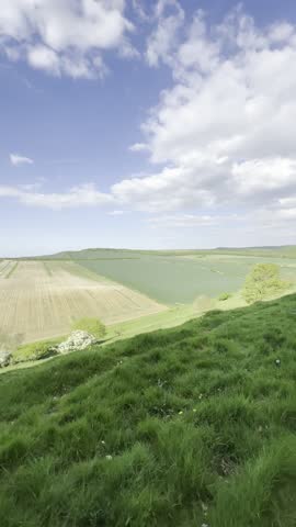 Vertical video of a green valley and gentle hill on a sunny day in the South England countryside, capturing peaceful and scenic rural beaut