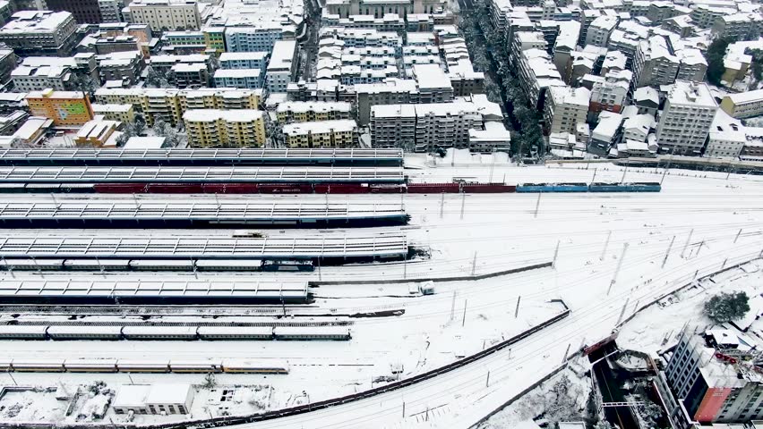 Snow blankets railroad tracks in a stunning aerial view of a winter landscape
