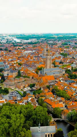 Vertical video. Bruges, Belgium. Church of Our Lady - Gothic church from the 13th century. Panorama of the city center from the air. Cloudy weather, summer day, Aerial View, Point of interest. Rich c
