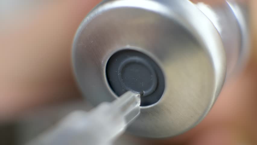 First responder hand extracts vaccine from vial into syringe. Public health and safety concept. Immunization campaigns to fight diseases. Healthcare workers supporting vaccination programs worldwide