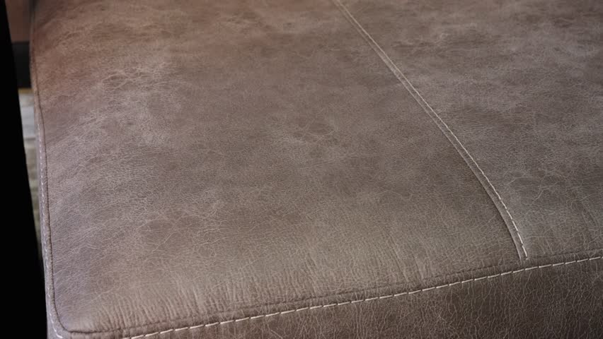 Palm presses and releases brown hide cushion, showing soft rebound detail