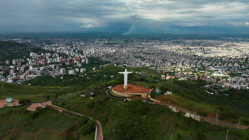 Establishing drone shot of the Cristo Rey statue, Cali city backdrop, in Colombia