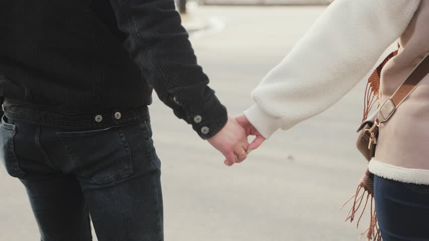 Happy couple in love, man and woman, holding hands and walking outdoors in winter.