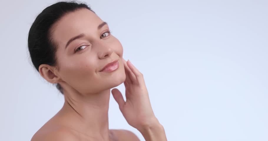 Confident Caucasian woman touches her smooth skin in a minimalist skincare scene. Perfect for dermatology clinics, anti-aging treatments, facial care, and cosmetic rejuvenation services.