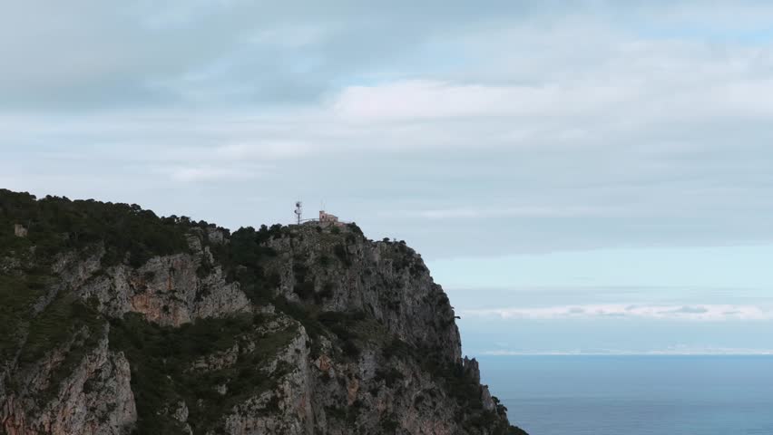 Capo Noli, Liguria, Italy - A Small Lighthouse Crowns the Cliff’s Edge, Standing Tall as a Silent Guardian Over the Vast, Open Sea - Orbit Drone Shot