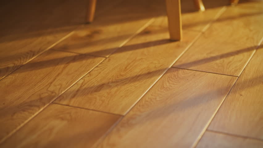 Close-up of bare feet against a wooden floor. A man walks barefoot on the floor. Footsteps with bare feet. The action takes place in a bright room filled with sunlight in the early morning