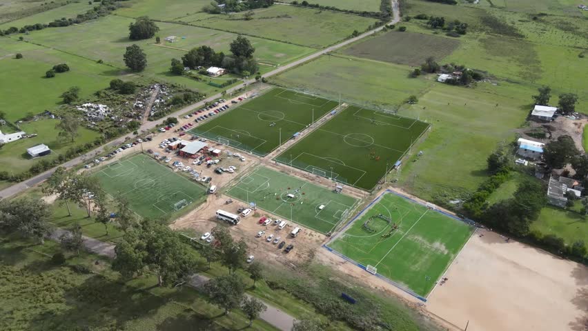 Multiple soccer fields host amateur matches in a rural area, providing a hub for sports and community