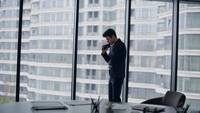 Pensive businessman thinking on career standing by office window looking cityscape view. Focused professional pondering strategy holding smartphone. Determined executive making important decisions. - Powered by Shutterstock - Get 15% off with code: PIKWIZARD15