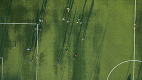 Aerial view of a youth soccer training session on a green field with long shadows cast by players in the late afternoon sun - Powered by Shutterstock - Get 15% off with code: PIKWIZARD15