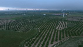 Tracking shot moving sideways past a wind turbine at sunrise, highlighting the rotor and geometric crop patterns across a vast renewable energy landscape - Powered by Shutterstock - Get 15% off with code: PIKWIZARD15