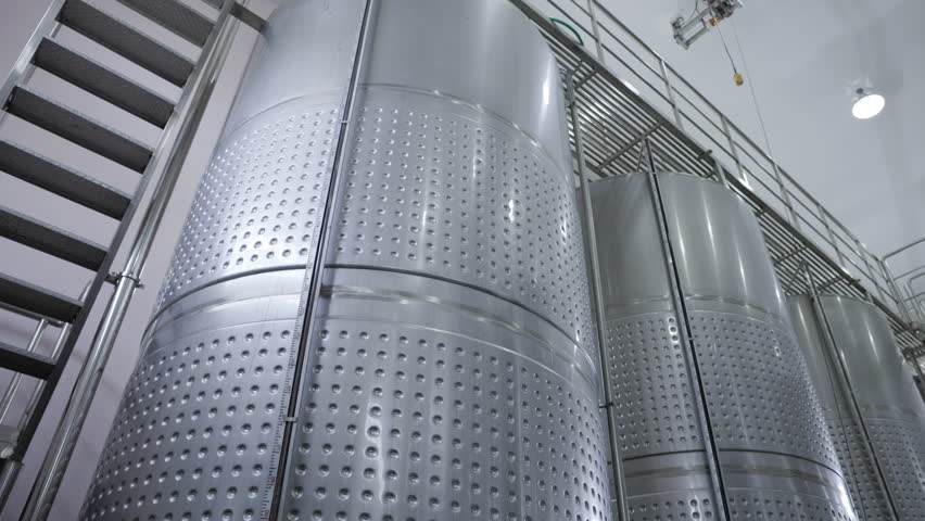 Background and banner : whiskey or brandy warehouse. stainless wine barrels in the cellar of winery warehouse factory 