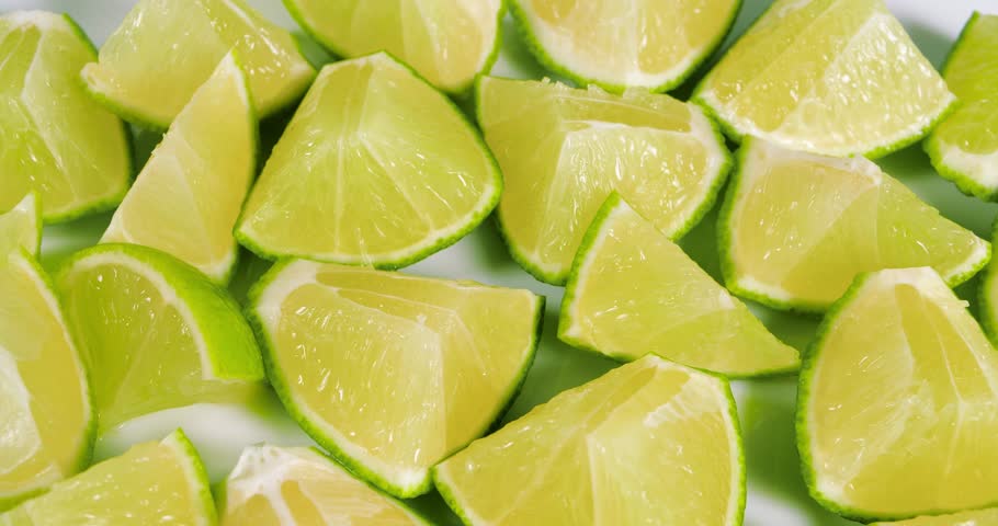 Ripe Lime Fruits with Slices and Lime Halves Slowly Rotating on a White Background. Macro Video Shooting