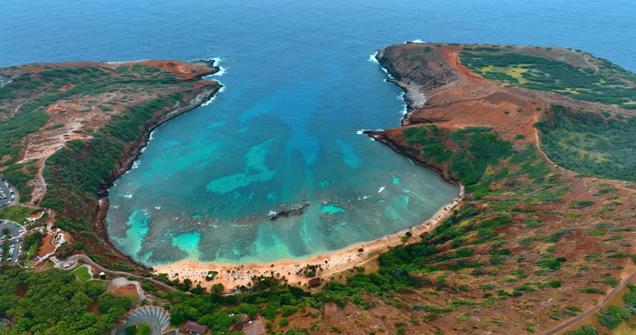 People rest on the sandy beach in Hanauma Bay in Honolulu, Hawaii, USA. Drone flight over the stunning landmark at daytime.