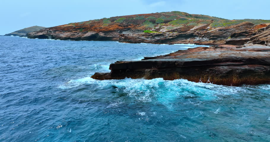 Waves of the Pacific Ocean hitting the rocks at the coast. Drone footage over the waterscape revealing view of the rocky shore of Oahu, Hawaii, USA.