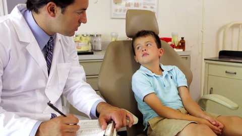 Dentist asks young male patient questions and writing down responses before asking him to show his teeth. Shot on Canon 5d Mk2 with a frame rate of 30fps