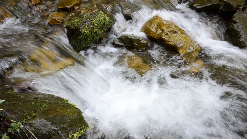 Mountain stream, water flow through color stones