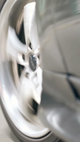 wonderful close view black car wheel drives on gray asphalt on underground parking lot reflecting light