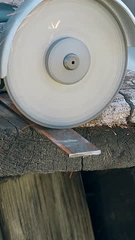 slow motion closeup powerful circular saw cuts part of metal plank under sparks shower on wooden table