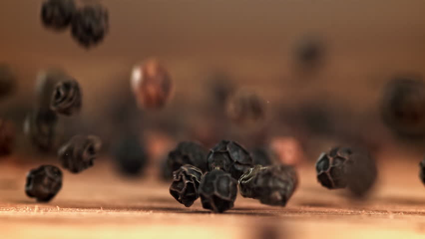 Black pepper falls on a wooden table. Filmed on a high-speed camera at 1000 fps. High quality FullHD footage