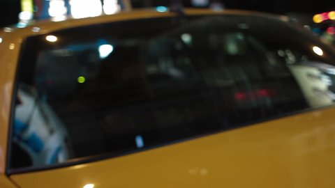 A woman exits a yellow New York taxi cab at night