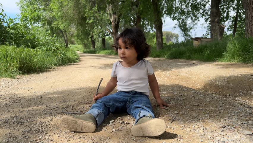 Toddler playing with stones on the forest path