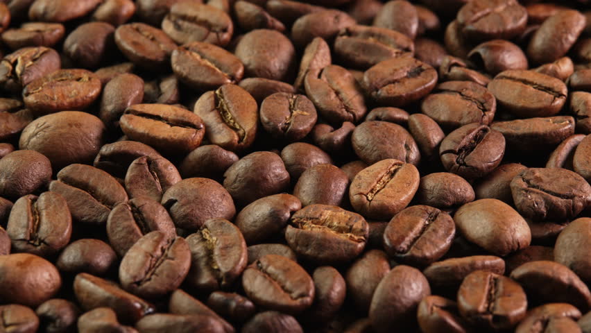 Roasted coffee beans rotating as background close-up side view. Concept for coffee shop with brown coffee beans rotating as background for advertising, promo, vending machine