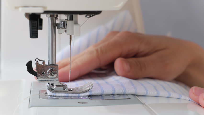 woman sews clothes on sewing machine. manufacture of dresses, shirts. hobbies professional sewing skills. factory for production of fashionable clothing collections. steel needle.